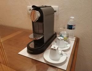a coffee maker sitting on a table with two cups at Logis Hotel Calisola Besançon - Soirée Etape - EuroVelo 6 in Chalezeule