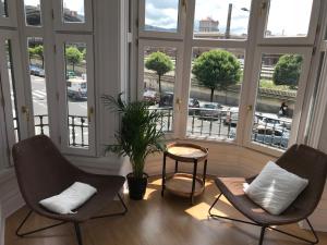 dwa krzesła i stół w pokoju z oknami w obiekcie Apartamento en el centro de Bilbao w mieście Bilbao