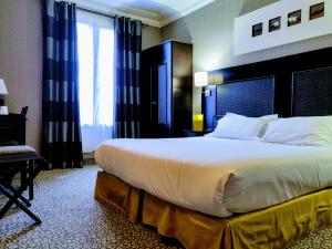 um quarto de hotel com uma cama grande e uma janela em Convention Montparnasse em Paris