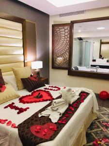 Ramada by Wyndham Dammam Khaleej Road في الدمام: غرفة نوم بها سرير كبير وعليها زهور حمراء