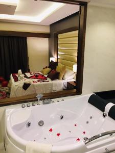 a bathroom with a bath tub in front of a bed at Ramada by Wyndham Dammam Khaleej Road in Dammam