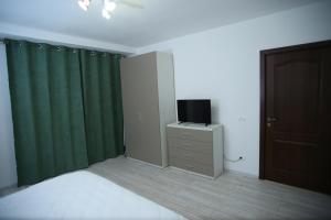 a bedroom with green curtains and a television on a dresser at RCC2 in Focşani