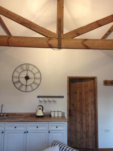 a kitchen with a clock on the wall and a window at Little Banks Barn in Ringwood