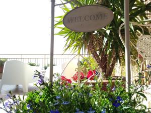 a sign that says welcome in a garden with flowers at B&B Portatenea in Agrigento