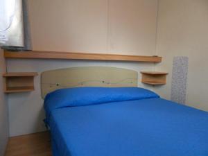 a bedroom with a blue bed with wooden shelves at CAMPEGGIO PARCO DEI PINI in San Feliciano