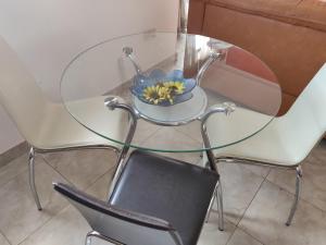 una mesa de cristal con un tazón de flores en una silla en Panoramic Penthouse in Marsascala which enjoys sea and country views, en Marsaskala