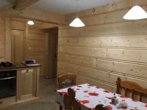 a dining room with a table and a wooden wall at Domek pod Maciejową in Rabka-Zdrój