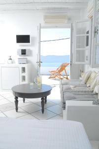 a white living room with a table and a couch at Archondoula Studios in Plaka Milou
