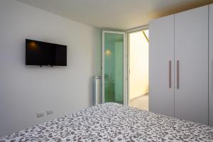 1 dormitorio con 1 cama y TV en la pared en Alex's House Fregene, en Fregene