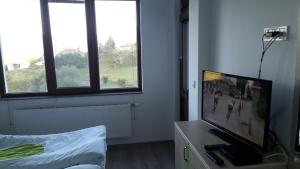 a room with a flat screen tv and windows at Guest House Panorama in Gela