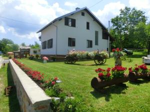une maison blanche avec des fleurs dans la cour dans l'établissement Pansion Izvor, à Korenica