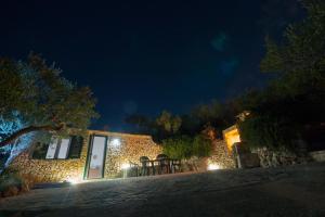 a stone house with a table and chairs at night at Olive Tree House - Charme Homes in Sutivan