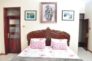- une chambre avec un lit en bois et 2 oreillers dans l'établissement Plot 4 Kavuma Close, à Kampala