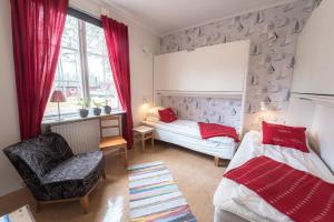 a bedroom with two beds and a chair and a window at Hasselö Hostel in Hasselö