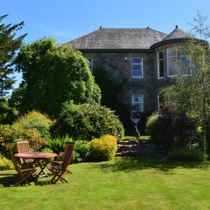 a house with a table and chairs in the yard at Balnearn House in Aberfeldy