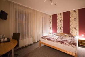 a bedroom with a bed with red walls and a table at Hotel Katrina in Cēsis