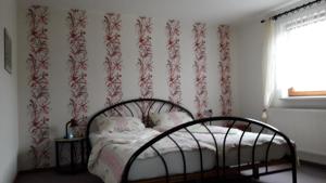 - une chambre avec un lit et du papier peint rouge et blanc dans l'établissement Ferienhaus Greiling, à Quedlinbourg