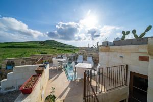 Un balcón con mesas y sillas en un edificio en Ta Pinu Guesthouse en Għarb