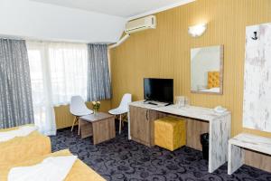 a hotel room with a tv and a desk with chairs at Family Hotel Prestige in Burgas