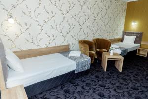 a hotel room with two beds and two chairs at Family Hotel Prestige in Burgas City