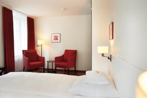 a hotel room with two red chairs and a bed at Boutique Hotel Helmhaus Zürich in Zurich