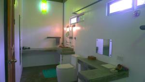 
a bathroom with a toilet, sink, and mirror at SomeWhere Else Boutique Resort in Mambajao
