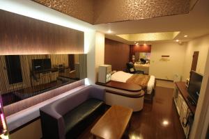 a hotel room with a bed and a couch and a television at Hotel Gem Oyama Adult Only in Honden