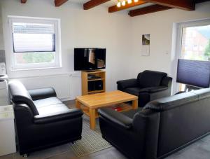 ein Wohnzimmer mit Sofas, einem Tisch und einem TV in der Unterkunft Ferienhaus Krabbe in Friedrichskoog-Spitze/ Nordsee in Friedrichskoog