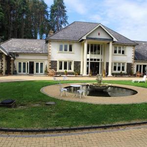 a house with a fountain in the middle of a yard at Plas Y Dderwen Apartments in Aberystwyth