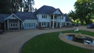 a large white house with a fountain in the yard at Plas Y Dderwen Apartments in Aberystwyth +14 photos