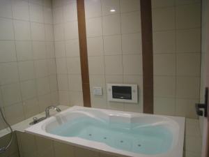 a bath tub in a bathroom with a microwave at Hotel Gem Oyama Adult Only in Honden