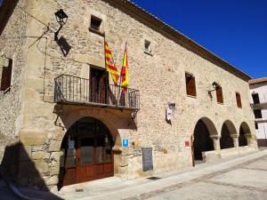 een stenen gebouw met twee vlaggen op een balkon bij Hotel Rural Curia in El Castellar