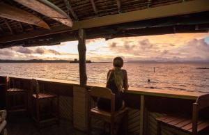 a woman sitting at a bar looking out at the ocean at Imagination Island in Gizo