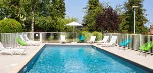 a swimming pool with lounge chairs and a fence at Golden Tulip Troyes in Barberey-Saint-Sulpice