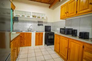 cocina con armarios de madera y estufa negra en Protea Park Self Catering Guesthouse, en Rustenburg
