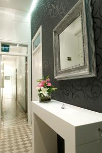 baño con espejo y flores en una encimera en B&B Castiglia, en Palermo
