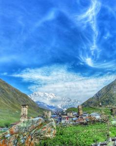a small town in a valley with snow capped mountains at Guest House Buba in Ushguli +35 photos