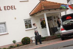 a woman standing outside of a house with a suitcase at Hotel Edel in Haibach