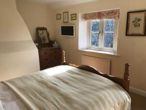 a bedroom with a bed with a dresser and a window at The Long House in Cirencester