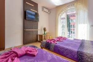 a bedroom with two beds with purple sheets and a tv at Guesthouse Sunny in Soko Banja