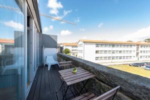 uma varanda com um banco de madeira e um edifício em Fontaínhas Stylish Apartment by DA'HOME no Porto