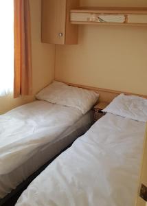 two beds in a small room with a window at 4 Berth with private Garden - 58 Brightholme Holiday Park Brean! in Brean