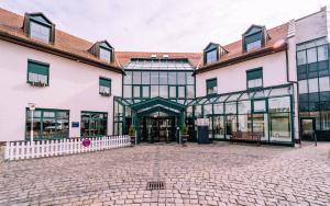 a large building with glass doors and a brick courtyard at Atomis Hotel Munich Airport by Mercure in Oberding