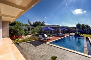 een zwembad met stoelen en parasols in de achtertuin bij Villa Luna Kuta Lombok in Kuta Lombok