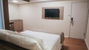 a bedroom with a bed and a flat screen tv at Hotel Golden Inn Lafaiete in Conselheiro Lafaiete