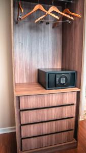 a microwave sitting on top of a wooden shelf at Hotel Golden Inn Lafaiete in Conselheiro Lafaiete