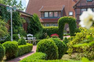 einen Garten mit Büschen und ein Haus mit einem Gebäude in der Unterkunft Hotel Altes Land in Jork