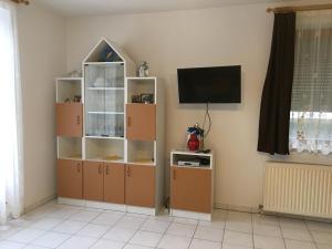 a living room with a television and a book shelf at Badacsony Apartmanház in Badacsonytomaj