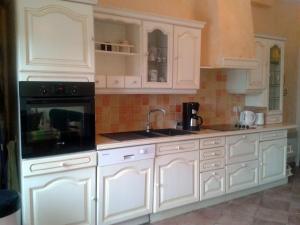 a kitchen with white cabinets and a sink at le gite du jardinier in Saint-Martin-lʼAiguillon +11 photos