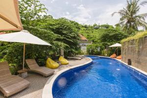 a pool with chairs and umbrellas next to a house at Aura Villa & Spa Amed Bali in Amed